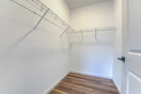 Spacious walk-in closet with modern shelving and elegant hardwood flooring.