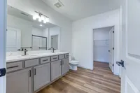 Modern bathroom featuring a double sink vanity with sleek fixtures, elegant lighting, and a spacious walk-in closet.