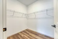 Spacious walk-in closet with sleek wooden floors and wire shelving for organized storage.