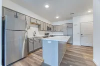 Modern kitchen with sleek cabinetry, stainless steel appliances, and a spacious island set against elegant hardwood flooring.