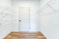 Bright and spacious walk-in closet with sleek white shelving and modern design, perfect for organizing and storage.