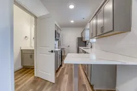 Modern kitchen with elegant white countertops, sleek gray cabinets, and wooden flooring, perfect for culinary enthusiasts.