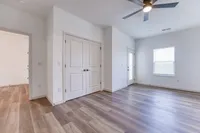 Bright and spacious room with elegant wood flooring, modern ceiling fan, and ample natural light from large window and glass door.