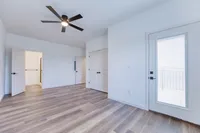 Bright and spacious bedroom with elegant hardwood flooring, modern ceiling fan, and access to a private balcony.