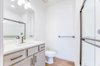 Bright and modern bathroom featuring sleek marble countertops, elegant fixtures, and a spacious shower.