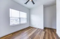 Bright modern room with elegant wood flooring and a large window featuring stylish blinds, perfect for creating a cozy living area.