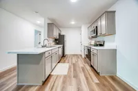 Modern kitchen with sleek cabinetry, spacious countertops, and stylish wooden flooring, perfect for culinary enthusiasts.