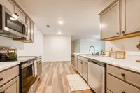 Elegant kitchen with modern cabinetry, sleek countertops, stainless steel appliances, and warm laminate flooring, creating a welcoming and functional cooking space.