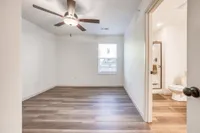Bright and inviting bedroom featuring elegant wood flooring, a modern ceiling fan, and access to a private bathroom.