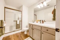 Elegant bathroom with modern glass shower, sleek marble countertops, and warm wooden flooring.