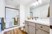 Modern bathroom with a glass-enclosed shower, elegant wood cabinetry, and sleek countertop. Bright lighting and tasteful decor create a luxurious and inviting atmosphere.