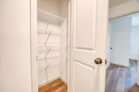 Spacious walk-in closet with sleek wire shelving and elegant hardwood flooring, designed for optimal organization and style.