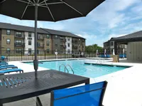 Inviting apartment complex with a luxurious swimming pool and modern seating area, perfect for relaxation and leisure.