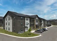 Modern apartment complex with sleek design, ample parking, and lush greenery under a vibrant blue sky.