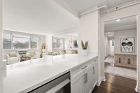Bright and inviting living space with elegant decor, large windows, and modern quartz kitchen counter detail at Parkside Place, apartments in Cambridge, MA