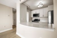 Modern kitchen with sleek statuario quartz countertops, white cabinets, stainless steel appliances, and gas stove for a sophisticated look at Parkside Place, apartments in Cambridge, MA