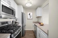Modern kitchen with six-burner gas stove, sleek stainless steel appliances, elegant cabinetry, stone countertops and large refrigerator at Parkside Place, apartments in Cambridge, MA