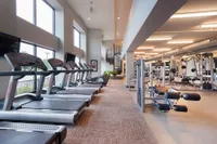 Bright and modern fitness center with state-of-the-art equipment, ample natural light, and a sleek spiral staircase.