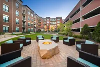 Chic outdoor courtyard with modern seating and a central fire pit, surrounded by contemporary brick apartment buildings, offering a serene and inviting environment for relaxation.
