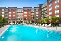 Contemporary apartment complex with a luxurious pool area, modern lounge chairs and vibrant landscaping, perfect for relaxation and leisure.