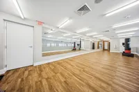 Modern fitness studio with sleek wooden flooring, large mirrors, and high ceilings, perfect for workout classes or personal training.