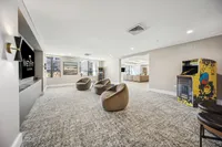 Modern lounge area featuring cozy swivel chairs, a retro arcade game, and vibrant artwork in a spacious, well-lit room at Ninety7Fifty On The Park.