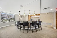 Modern communal bar area with stylish pendant lighting, comfortable seating, and large window offering a bright, inviting atmosphere.