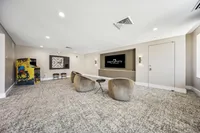 Chic entertainment lounge with cozy seating, vintage arcade game, and sleek screen at Ninety7Fifty on the Park.