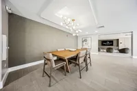 Modern dining room with elegant wooden table and sleek chairs, featuring a contemporary chandelier and stylish neutral decor.