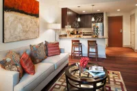 Modern apartment interior featuring a cozy living room with elegant decor, open kitchen with dark wood cabinetry, and stylish breakfast bar seating.