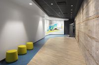 Modern hallway with vibrant wall art and stylish seating, featuring a blend of rustic brick and sleek design.
