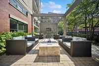 Chic outdoor lounge area with comfortable wicker sofas, elegant pergola, and lush greenery, perfect for relaxation and entertainment.