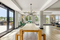 Bright and inviting modern apartment interior with large windows, elegant chandelier, and cozy seating area overlooking a spacious balcony.