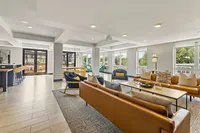 Modern and inviting open-concept community lounge featuring stylish seating, large windows, and chic decor, perfect for social gatherings and relaxation.
