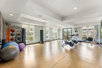 Bright and airy modern gym with wooden flooring, featuring exercise bikes, yoga balls, and state-of-the-art equipment under natural light.