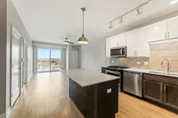 Modern open-concept kitchen and living area with sleek appliances, large island, and ample natural light from balcony view.