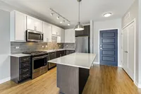 Modern kitchen with sleek stainless steel appliances, elegant quartz countertops, and stylish two-tone cabinetry complemented by wood flooring and sophisticated lighting.