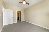 Bright and inviting bedroom with soft carpet, modern ceiling fan, and ample closet space, perfect for relaxation.