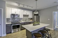Modern kitchen with sleek cabinetry, stainless steel appliances, a stylish backsplash, and a chic breakfast bar with pendant lighting.
