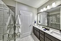 Elegant modern bathroom featuring double vanity, sleek mirrors, and a spacious glass shower with gray tile accents.