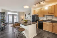 Chic open-plan apartment featuring a modern kitchen with wooden cabinetry, cozy living area, and abundant natural light.