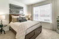 Cozy bedroom with elegant decor, featuring a plush bed and abundant natural light from large windows.