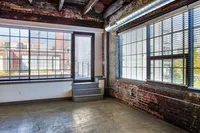 Chic urban loft with large windows, exposed brick walls, and industrial ceiling for a modern city vibe.