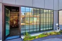 Contemporary apartment exterior with large windows and lush planter box, showcasing urban design and outdoor charm.