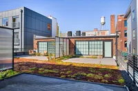 Chic urban terrace with modern architecture, lush green rooftop garden, and comfortable outdoor seating.