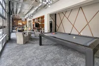 Modern lounge area with elegant pool table, stylish seating, and contemporary lighting in a bright, spacious setting.