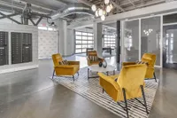 Modern industrial-style lounge with cozy mustard armchairs, chic lighting, and mailboxes, offering a stylish communal space.