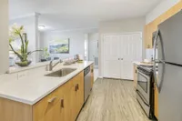 Modern kitchen with sleek stainless steel appliances, elegant light wood cabinets, and a spacious island overlooking a cozy dining area.