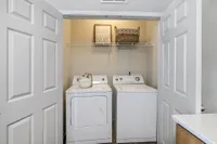 Charming laundry nook with modern washer and dryer, accented by a decorative basket and inspirational wall art.