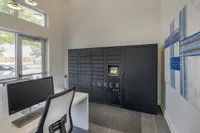Modern apartment lobby featuring secure Luxer One package lockers and a sleek computer station, enhancing convenience and style.